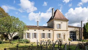 A stone building with a pitched roof, a chimney, and a large window.