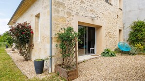 A stone building with a gravel driveway, a wooden planter, and a blue chair.