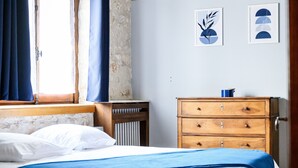 Un dormitorio con cama, cómoda de madera y una obra de arte en la pared.