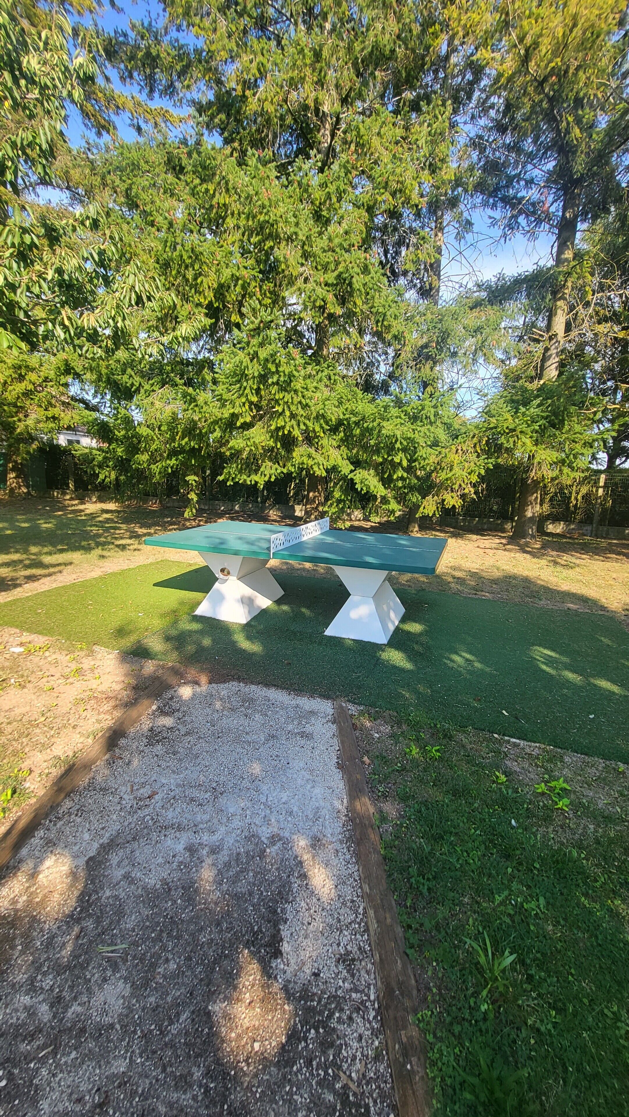 Un espace extérieur aménagé avec des sièges, un chemin de gravier et entouré d’arbres et d’herbe.