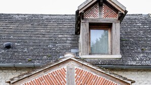 Un bâtiment rustique avec une porte en bois, une petite fenêtre et un mur en pierre.