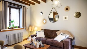 Un salon chaleureux avec un canapé marron, une table basse en bois et un coin repas comprenant une table et des chaises.