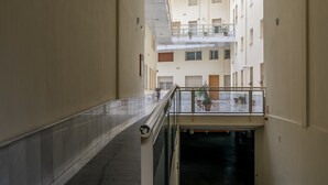 A corridor with a glass railing, a staircase, and a view of multiple floors with balconies.