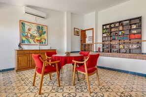 A dining area with a round table, red chairs, a wooden cabinet, and a bookshelf. - Villa 'Leonor Con Piscina Privada' with Mountain View, Wi-Fi and Air Conditioning (Monachil)