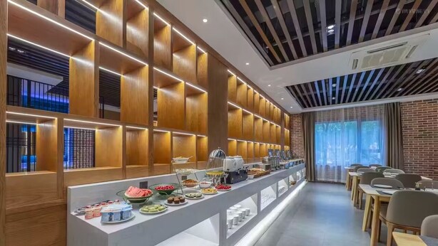 A modern breakfast bar with a variety of food items and a seating area with tables and chairs.