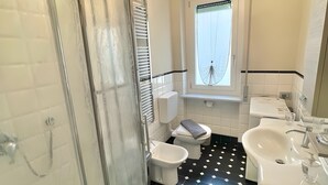 Un baño con ducha, inodoro, bidé y lavamanos.