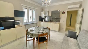 Una cocina moderna con una mesa de comedor, sillas, una araña y un sofá.