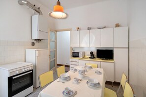 Une cuisine compacte équipée d’une cuisinière, d’un four, d’un four à micro-ondes et d’une table à manger pour quatre personnes.