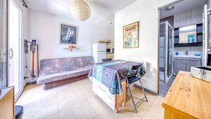 A compact room with a sofa, a small table, a kitchenette, and a window.