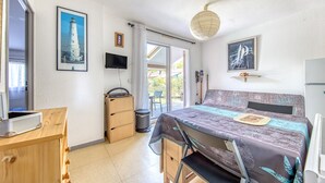 A bedroom with a bed, a desk, a chair, a TV, and a window with a view.
