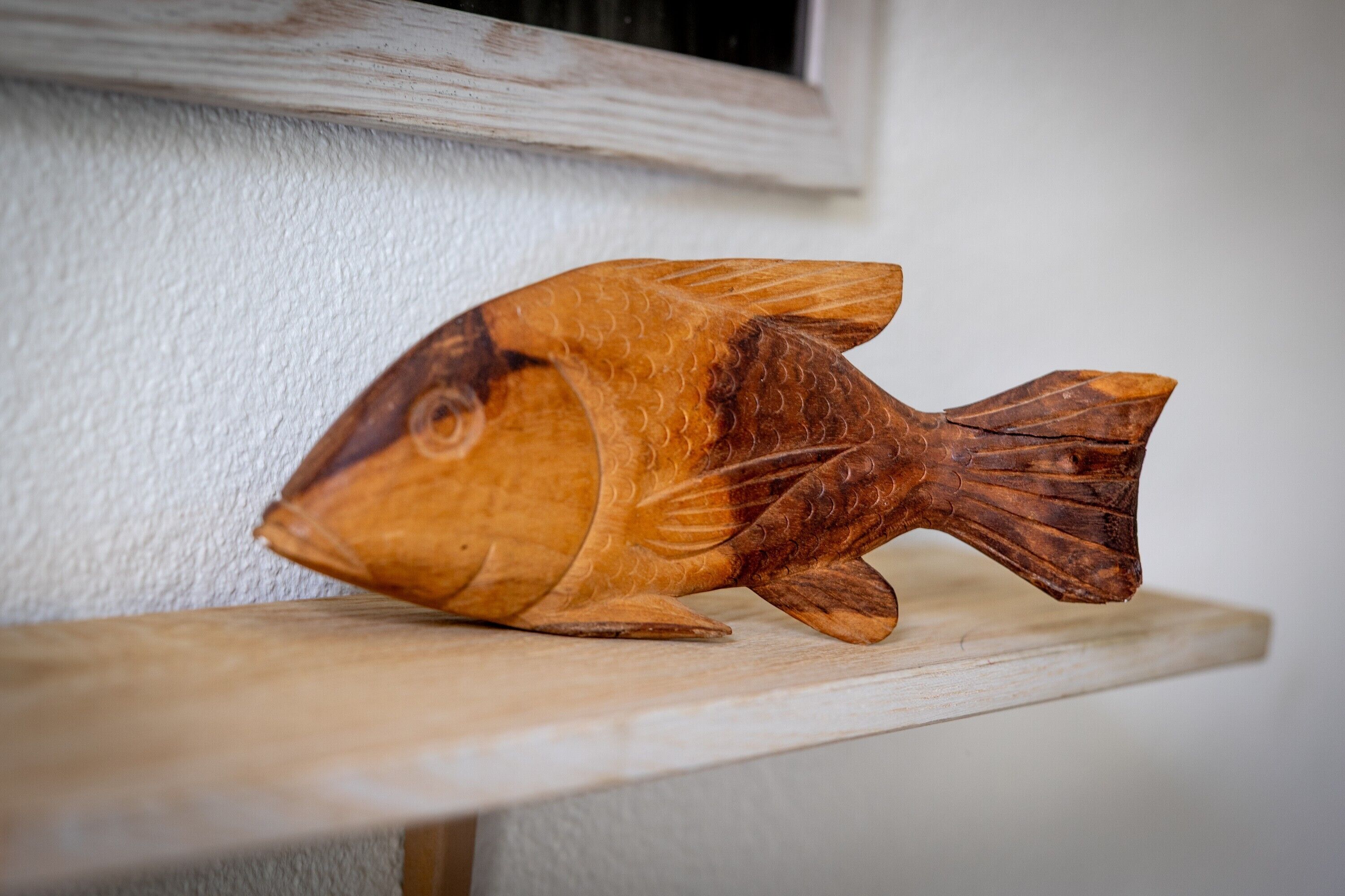 A wooden fish sculpture on a shelf.
