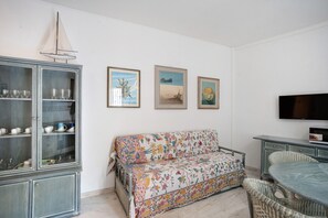 A living room with a sofa, a cabinet with glass doors, and a flat-screen TV. - Apartment 'Riviera' with Balcony, Wi-Fi and Air Conditioning (Sanremo)