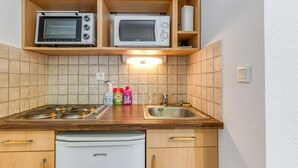A compact kitchen with a stove, microwave, and sink. - Apartment 'B3 Chamois' with Mountain View, Shared Garden and Wi-Fi (Le Bourg-d'Oisans)