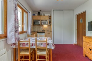 Eine kompakte Küche mit Holzausstattung, einer Mikrowelle und einem Essbereich mit Tisch und Stühlen.