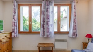 Une pièce avec une table en bois, un lit, une commode et une fenêtre avec des rideaux.