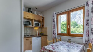 Ett kompakt kök med diskmaskin, mikrovågsugn och ett bord med ett rutigt bordsduksöverdrag.