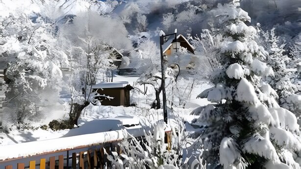 A snow-covered mountain with a ski lift, a wooden cabin, and a clear blue sky.