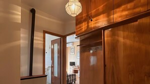 Un couloir avec des armoires en bois, un sol en marbre et un luminaire suspendu.