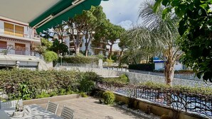 Une terrasse extérieure avec une table et des chaises, un mur en pierre et une vue sur une étendue d’eau et des bâtiments en arrière-plan.