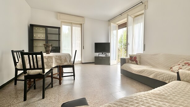 A room with a bed, a TV, a table with chairs, and a cabinet. - Apartment 'Alice' with Sea View, Balcony and Wi-Fi (Sanremo)
