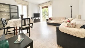 A modern living room with a dining area, a flat-screen TV, and a sofa with decorative pillows. - Apartment 'Alice' with Sea View, Balcony and Wi-Fi (Sanremo)
