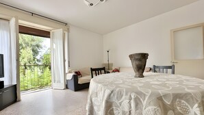 A spacious room with a large bed, a dining table, and a view through a sliding door to the outdoors. - Apartment 'Alice' with Sea View, Balcony and Wi-Fi (Sanremo)