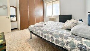 A bedroom with a bed, a wardrobe, a mirror, and a window. - Apartment 'Alice' with Sea View, Balcony and Wi-Fi (Sanremo)