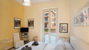 A hotel room with a bed, a TV, a small table, a chair, and a view of the outside balcony. - Apartment 'La Terrazza Di Sabrina' with Private Terrace, Balcony and Wi-Fi (Sanremo)