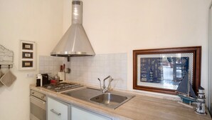 A kitchen with a stainless steel sink, a range hood, and a window with a decorative view. - Apartment 'La Terrazza Di Sabrina' with Private Terrace, Balcony and Wi-Fi (Sanremo)