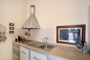 Una cocina con un lavamanos de acero inoxidable, una campana extractora y un ventanal con vistas decorativas.