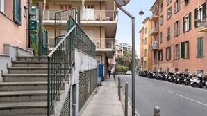 A multi-story building with a staircase leading to a balcony, a sidewalk, and parked motorcycles along the street. - Apartment 'La Terrazza Di Sabrina' with Private Terrace, Balcony and Wi-Fi (Sanremo)