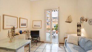 A living room with a glass table, a sofa, a TV, and a door leading to an outdoor patio with a table and chairs. - Apartment 'La Terrazza Di Sabrina' with Private Terrace, Balcony and Wi-Fi (Sanremo)