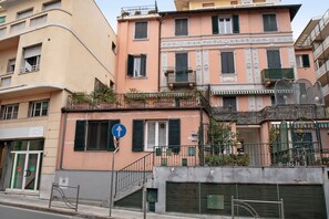 Un immeuble à plusieurs étages doté de balcons, d’une entrée bien visible et d’un panneau de signalisation bleu.