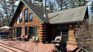 Uma cabana de tronco com um alpendre, área de estar externa e churrasqueira.
