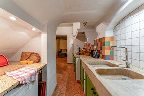 Een keuken met een aanrecht, twee spoelbakken, een rode stoel en een betegelde spatwand.
