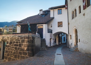 A stone wall, a building with a tiled roof, and a clear sky.