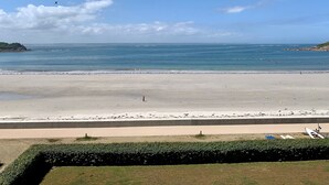 A beach with a clear sky, calm sea, and a distant rocky coastline. - Apartment 'Vue Mer By Madame Est Servie' with Sea View and Balcony (Trébeurden)