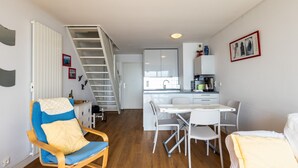 A modern apartment with a dining area, kitchen, and a staircase. - Apartment 'Vue Mer By Madame Est Servie' with Sea View and Balcony (Trébeurden)