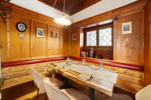 Een houten eetkamer met een lange tafel, banken en ingelijste foto's aan de muren.