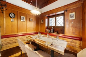 A wooden dining room with a long table, benches, and framed pictures on the walls. - Room 'Junior Suite 2' with Mountain View and Wi-Fi (Merano)