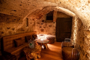A rustic stone-walled room with a wooden bench, a round glass table, and a cushioned bench. - Room 'Junior Suite 2' with Mountain View and Wi-Fi (Merano)