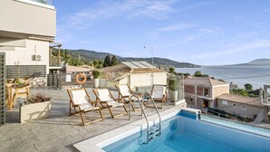 A rooftop swimming pool with lounge chairs, a view of the sea, and surrounding buildings. - Apartment 'Oceanida' with Sea View, Wi-Fi and Air Conditioning (Nikiana)