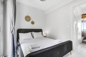 Un dormitorio moderno con una cama grande, una mesita de noche y una lámpara de pared.