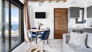 A modern living room with a dining area, a kitchen, and a large sliding glass door to a balcony. - Apartment 'Oceanida' with Sea View, Wi-Fi and Air Conditioning (Nikiana)