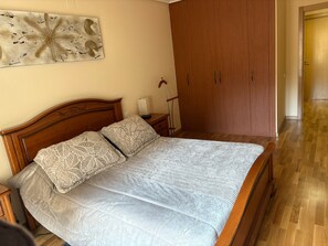 Un dormitorio con una cama de madera, una mesita de noche, una lámpara y un armario.