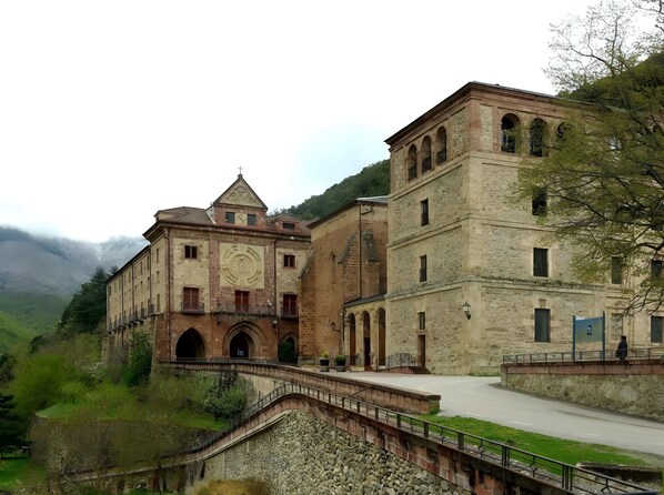 A historic building with a prominent clock tower, arched windows, and a stone bridge leading to the entrance.