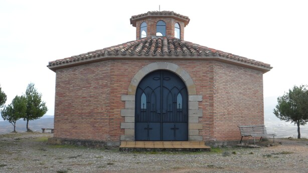 Un petit bâtiment en briques, doté d’une grande porte en arc de cercle et d’un clocher.
