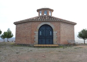 Un pequeño edificio de ladrillo con un gran arco de entrada y una torre con campana.