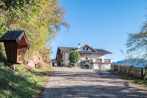 Une maison avec une allée en gravier, une clôture en bois et une vue sur les montagnes.