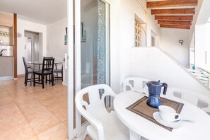 Un coin repas avec une table ronde, des chaises blanches, une machine à café et une tasse.